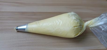 裱花袋装入8齿的裱花嘴、将面糊装入裱花袋、攥紧袋口。