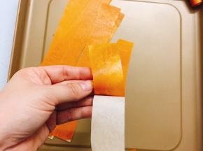 将烤好的果泥取出烤盘，用刀切成宽长条，撕掉油纸