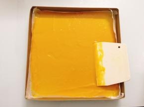 将芒果泥平均分配在两个烤盘里面，利用刮板将芒果泥平铺均匀，薄薄的一层就可以