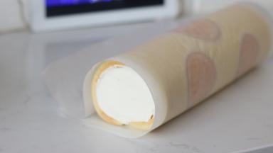 25. 连同油纸，利用擀面杖辅助卷起，收紧，然后一起放入冰箱冷藏个把小时定型后开切吧~