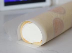 25. 连同油纸，利用擀面杖辅助卷起，收紧，然后一起放入冰箱冷藏个把小时定型后开切吧~
