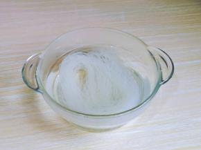 首先把龙口粉丝用冷水冲洗，放入玻璃容器中，加入开水，泡软。