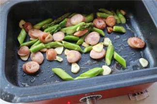 再放入芦笋煎一下，再放入香肠片煎熟，这个香肠里有芝士粒，容易糊，所以要用小火煎。煎好的香肠片看着就很有食欲。