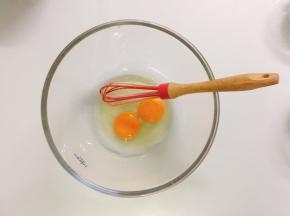 将两个鸡蛋倒入容器中，用打蛋器打散