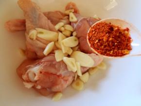 鸡翅根放入蒜片，放入辣椒粉