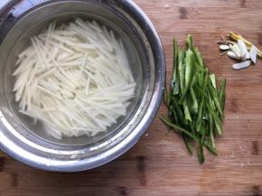 土豆切丝泡水中，除去多余淀粉，青椒切丝，蒜切瓣，生姜切丝