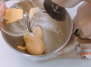 面团表面揉至表面光滑后加入软化的黄油，开低档揉至黄油完全融合于面团