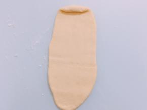 醒好的面团擀成长舌后卷成圆柱形