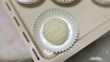 在面团表面喷层水，沾白芝麻后放纸托上，也可以直接放烤盘上，然后进行二发，发酵至两倍大。(也可以直接二发好后表面喷点水，撒一些白芝麻)