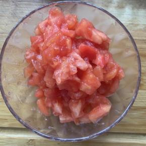 3、番茄用热水在锅里煮一分钟，去皮，切成丁备用。