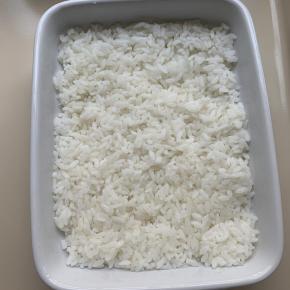 11、烤箱180度预热。取适量米饭，铺在焗碗中。