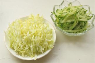 把配菜处理一下，黄瓜切成细丝，如果刀工不好，可以借助于擦丝器，圆白菜去掉中间的茎，切成细丝。圆白菜丝用开水烫一下，再过一下凉水待用。