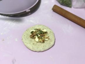 稍擀扁擀圆后放上适量奶酪馅和果仁碎。