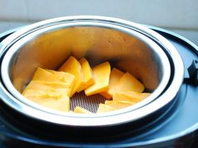 臻米脱糖养生饭煲内加入2杯清水，就用自带的量米杯就可以了。放好蒸网，切好的南瓜片放上去均匀地铺开，盖上盖子，选择“热饭”功能，12分钟。这个时间可以放心的去干别的事情了。