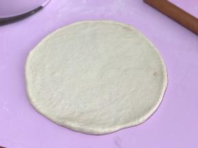 发好的面团排气揉圆按扁，擀成圆薄片，边缘稍厚些，静置5分钟。