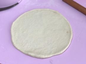 发好的面团排气揉圆按扁，擀成圆薄片，边缘稍厚些，静置5分钟。