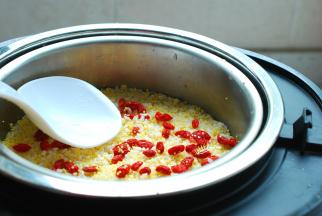 把枸杞子清洗干净放在米饭上面，用饭煲自带的饭勺整理平整。