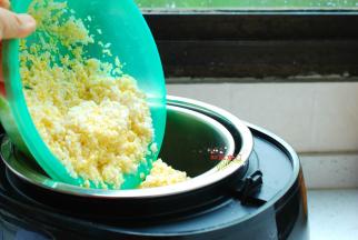 将淘洗干净的米饭平铺在饭煲的滤网上。