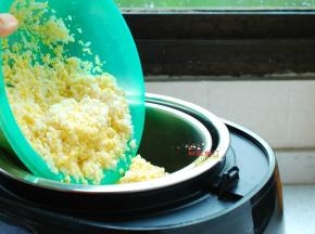 将淘洗干净的米饭平铺在饭煲的滤网上。