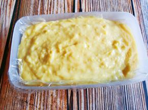 保鲜盒铺上保鲜膜，到入熬好的芒果奶糊，提起盒子震平，放冰箱冷藏四小时以上。