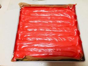 再将红丝绒蛋糊装入裱花袋中，无需裱花嘴，将其挤在原味蛋糊上，重点！用手指，沿着烤盘中回来划动，滑动过程中要让充分，要划到烤盘边缘。将烤盘调转方向，同样手法再划动一次。轻震烤盘，抹平