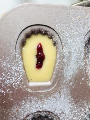 5、冷藏后的面糊需要回温一下。装入裱花袋中，无需花嘴，将面糊挤入模具中，挤到一半时将草莓果酱挤于中间位置，再覆盖一层面糊