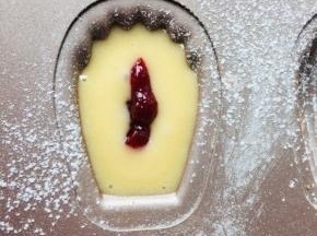 5、冷藏后的面糊需要回温一下。装入裱花袋中，无需花嘴，将面糊挤入模具中，挤到一半时将草莓果酱挤于中间位置，再覆盖一层面糊