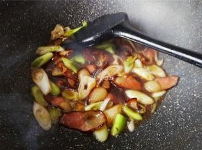 倒入点清水把腊肉煮制沸腾会，先把蒜白部分放入翻炒变软。