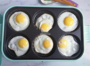 把鸡蛋磕入煎盘中，煎制的周边微黄，底部也是焦焦的微黄。