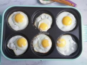 把鸡蛋磕入煎盘中，煎制的周边微黄，底部也是焦焦的微黄。