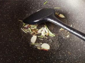 热锅倒入食用油，把蒜瓣切片，小葱切取葱白部分，放入锅中翻炒爆香。