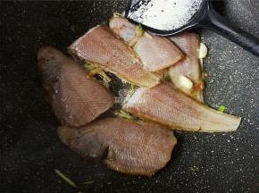 舌鳎鱼洗净，剔除鱼鳞（也可把皮剥离），把鱼切断放入锅中煎制。