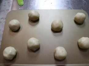 拿起一团切好的面团，轻轻的给它搓成圆球，然后放入烤盘内。