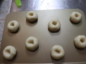 用食指轻轻的去戳一个洞，切记不能戳到旁边开裂，旁边开裂了以后，桃酥就不会成为一个圆形了，它会朝着开裂的地方去发展。