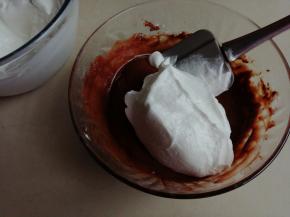 鸡蛋清分3次加入细砂糖，用电动打蛋器打发至偏干性发泡。取1/3打发好的蛋白霜到可可蛋黄糊里