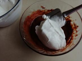 鸡蛋清分3次加入细砂糖，用电动打蛋器打发至偏干性发泡。取1/3打发好的蛋白霜到可可蛋黄糊里