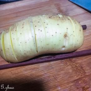 土豆带皮洗净，左右两边夹两根筷子，切片不切断，类似手风琴一般