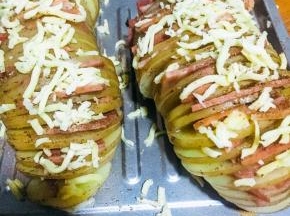 取出烤好的土豆，去除锡纸，每一片之间夹上培根，表面撒上芝士，放进烤箱200度烘烤15分钟即可。