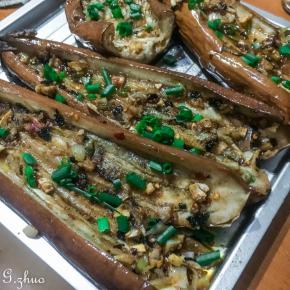 待茄子烤好后，取出中间划开，茄肉部分也可划上几刀方便入味，抹上淹料撒上葱花。，