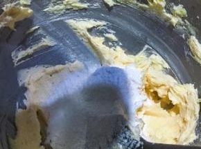 打匀后的黄油过筛加入蛋糕粉，扮匀至看不到干粉的状态，