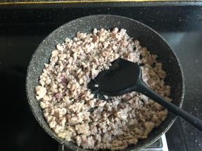 锅里加两勺植物油，倒入肉馅加一点点料酒炒至变色。
