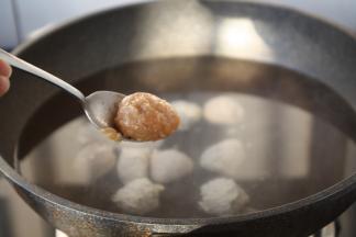 将水烧至八成热时关火，逐个将鸡肉丸子放入水中。