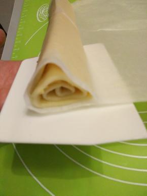 盖上油纸，把饼干面团塑型成三角形。用油纸把饼干面团卷起来，送入冰箱冷藏2小时以上，最好冷藏过夜。