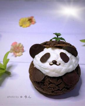 用巧克力酱在熊猫的脸上画出鼻子和嘴，脑袋上挤巧克力酱插上树叶或小花装饰。