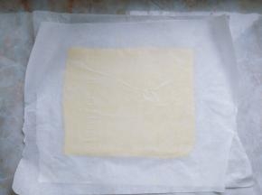 在厨师机揉面的同时，将片状黄油夹在两片油纸中间，擀成均匀的长方形片状，放入冰箱冷冻。