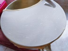 剪一块面团，用手拉扯四周，拉伸出均匀的薄膜，即完全扩展状态即可（不要用手揪面团，以免扯断面筋）。