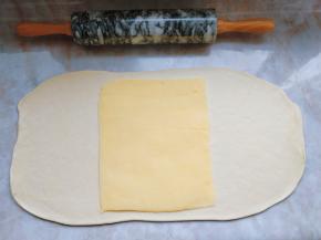 将冷冻好的面团取出，擀成黄油片的两倍大，把黄油片放在中间，两侧的面片朝中间折，在中间捏紧接缝。