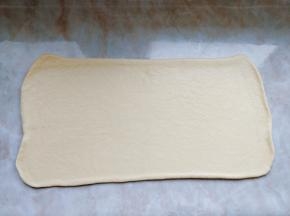 把面团旋转90度，沿接缝的方向把面片擀成0.5cm的厚片（先按压中间接口处来回滚动，然后再整块从头到尾擀动。擀面时要使用走锤，用力均匀，这样黄油夹层才能分布均匀）。