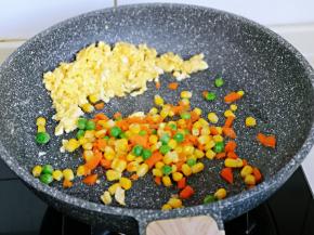 把鸡蛋碎放在锅旁边，加入焯水的彩蔬翻炒均匀。