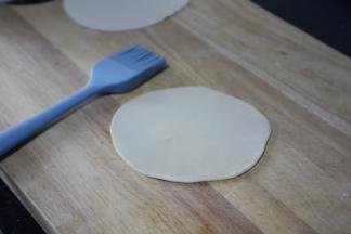 取两个面团压扁，用擀面杖擀大一些，在一个面团表面刷上薄薄的一层油。